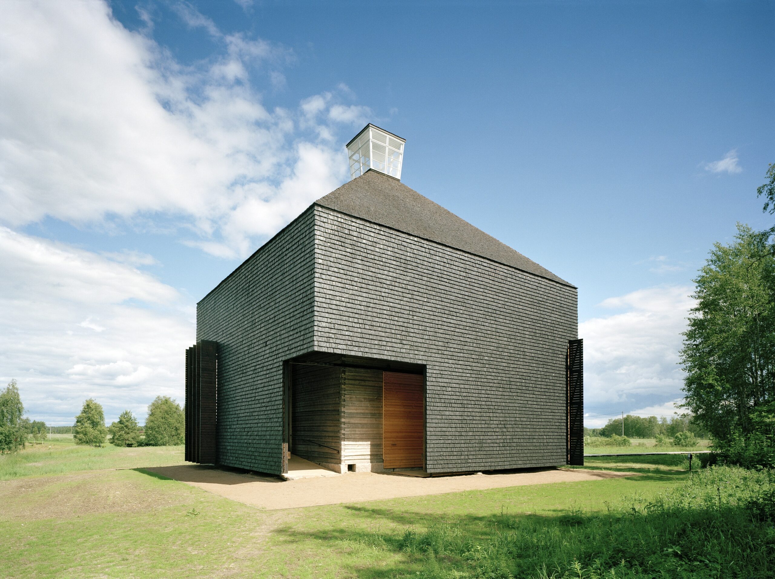 Kärsämäki Shingle Church showing the exterior shell clad with tarred shingles and the entry to the vestibule as a middle zone between the exterior and the interior 