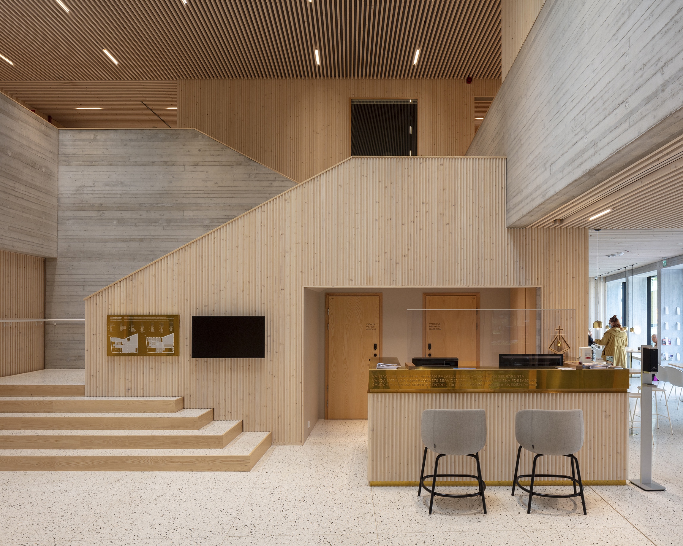 The central lobby of the Tikkurila Church showing the open stairs to the second floor on the left, the info desc in the middle and the cafe on the right