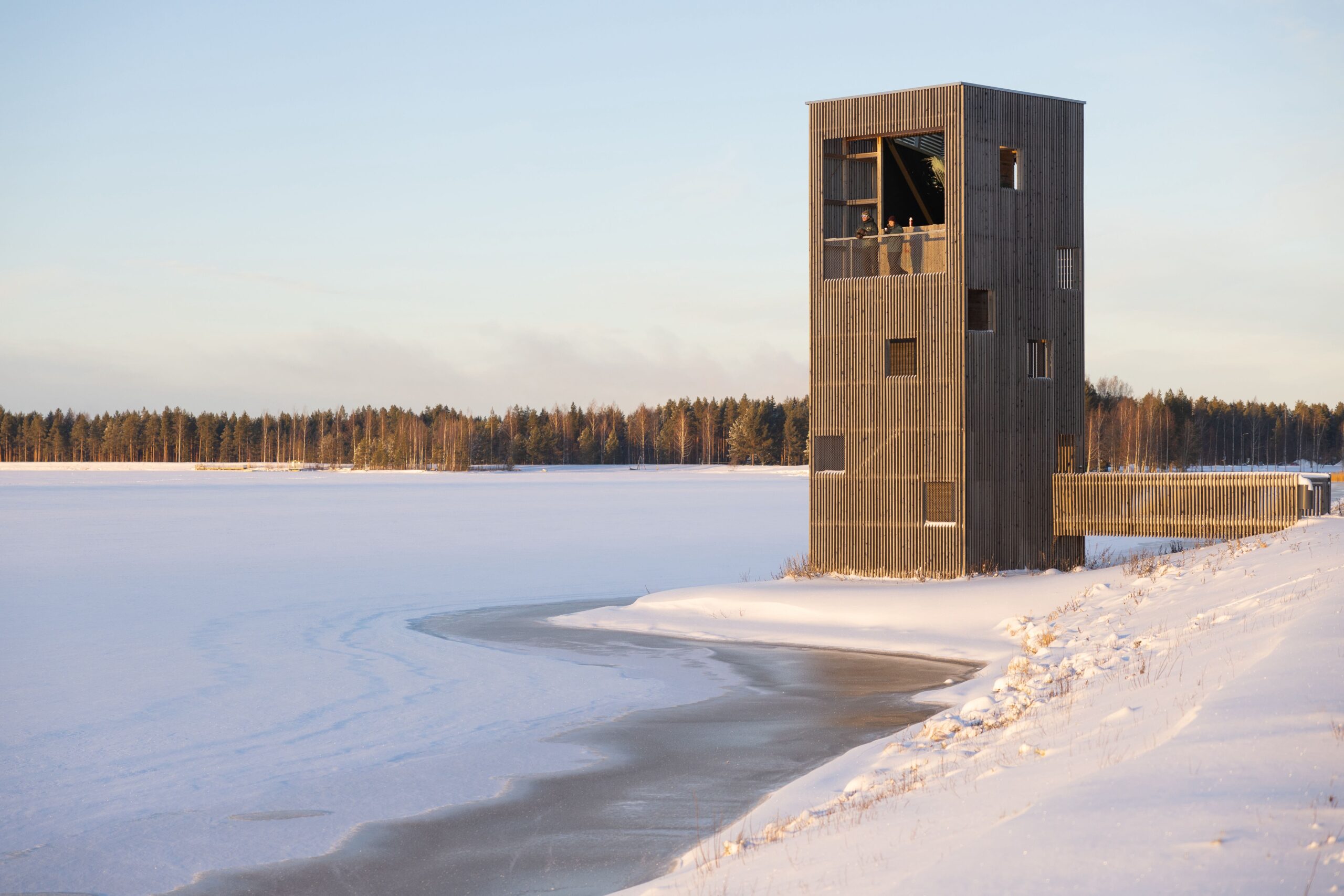 A wooden observation tower with a gigantic periscope on the lake shore in the winter