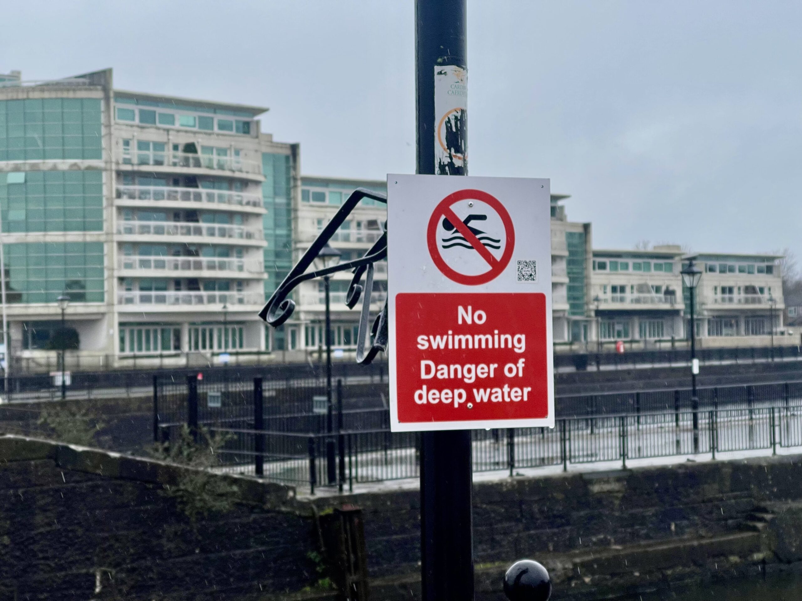 View of the Cardiff Bay with a sign "No swimming - Danger of deep water in the center